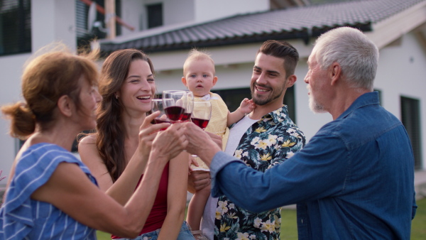 Three generations of family having a summer garden party gathering, modern house in background.