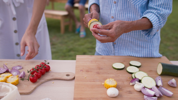 Close up of senior mother and adult daugter preparing vegetables for summer bbq grill garden party.