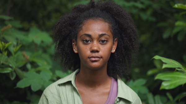 A multiracial girl looking at camera in forest, close-up