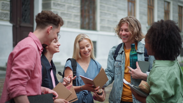 A group of happy teenagers together in front of school, back to school concept.