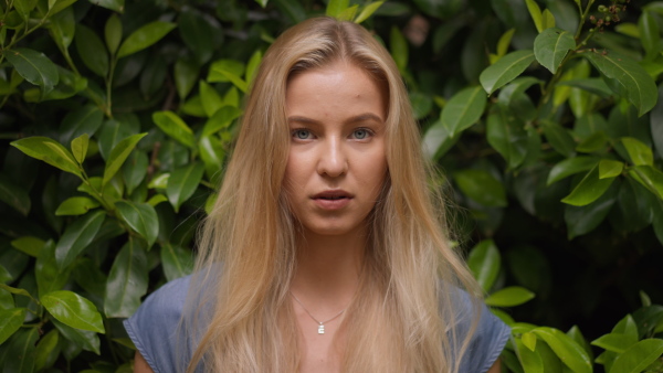 A tennager girl looking at camera in forest, close-up