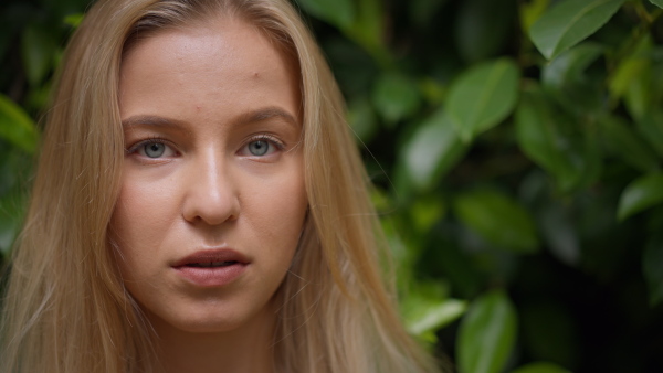 A tennager girl looking at camera in forest, close-up