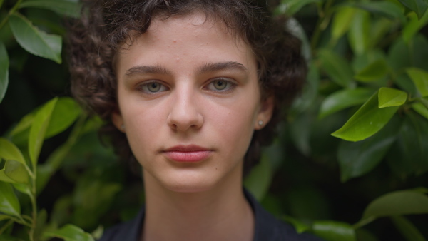 A tennager girl looking at camera in forest, close-up