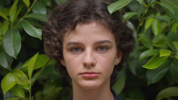 A tennager girl looking at camera in forest, close-up