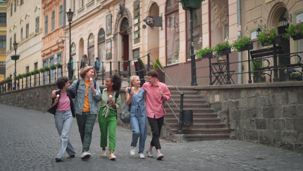 Group of friends enjoying nice time together in town, having an ice cream. Holiday, tourist concept.