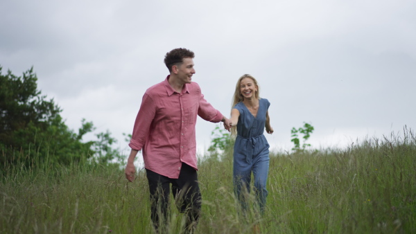 Happy teenage couple outdoor, running in the rain. Smiling and enjoying rainy weather.