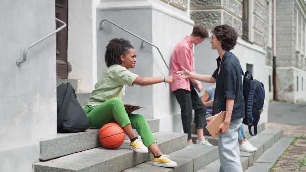 A group of happy teenagers together in front of school, back to school concept.