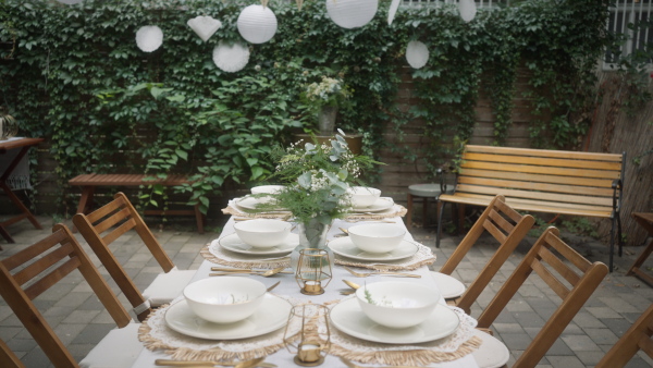 A festive wedding table setting with flowers at small reception in backyard in summer.