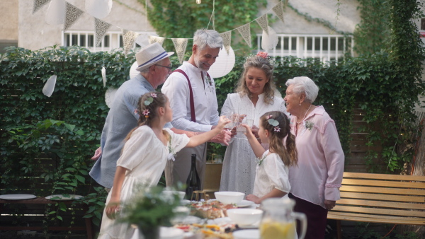 A mature bride and groom toasting with guests at wedding reception outside in the backyard.