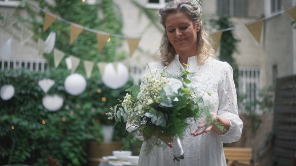 Mature bride looking at her beautiful wedding bouquet, outside in the backyard.