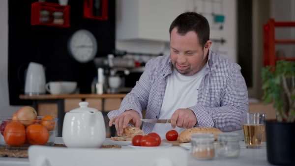 Independent man with down syndrome preparing a brekfast in his apartment.