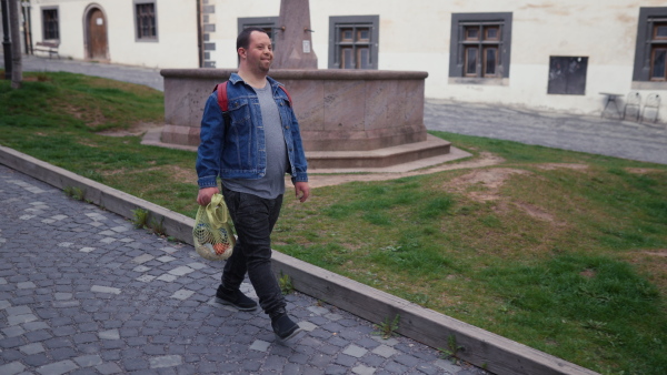 An independent young man with Down syndrome going back from gocery store with purchase.