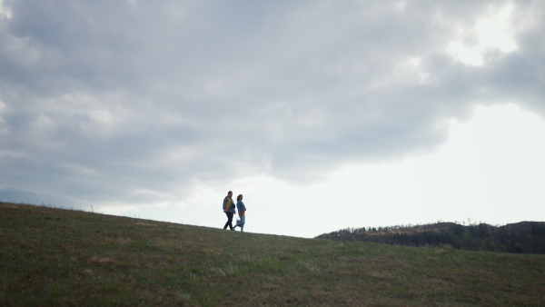 Happy young man with Down syndrome and his mother hiking together in a nature.