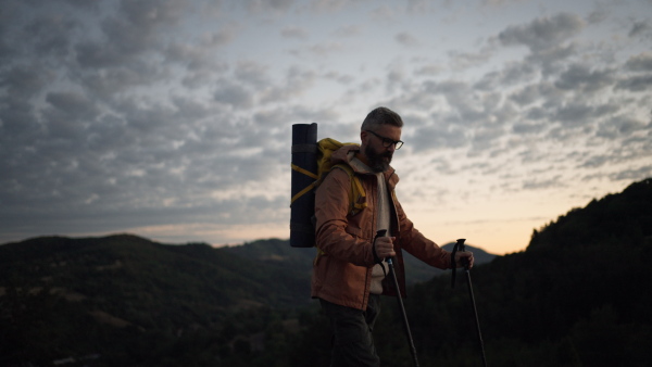 Mature man looking at view at top of a mountain at dusk.