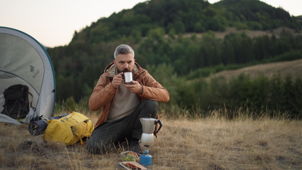 Man drinking coffe in nature while having a rest at hike.