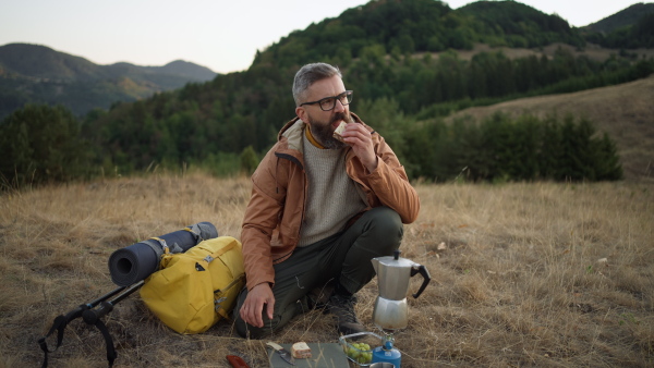 Male hiker eating sandwich having a rest in nature.