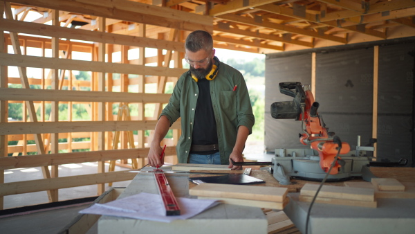 Carpenter working on buidling site of wooden eco house.