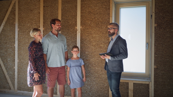 Family consulting new home with architect on building site of sustainable house.