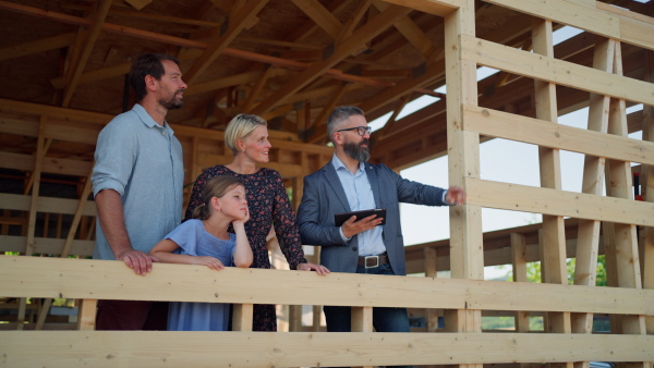 Family looking at view from new home with architect on building site of sustainable house.