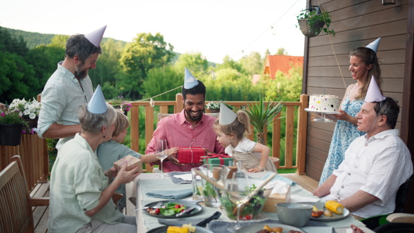 A multi generation family celebratiing birthday and have garden party outside in the backyard on patio.