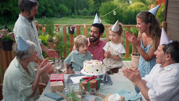 A multi generation family celebratiing birthday and have garden party outside in the backyard on patio.