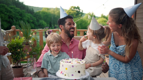 A multi generation family celebratiing birthday and have garden party outside in the backyard on patio.