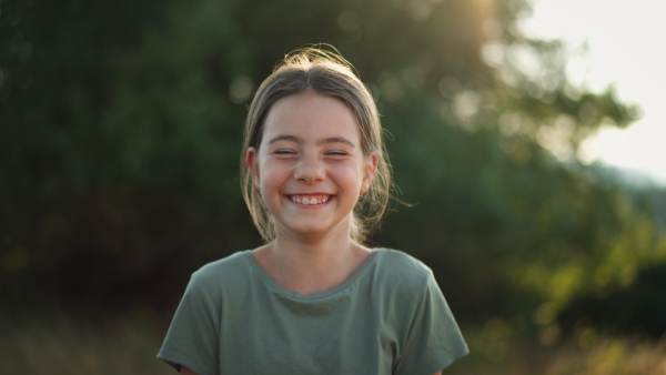 A video of a beautiful little girl laughing when having fun in summer in nature.