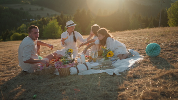 A happy family with children having picnic in park.