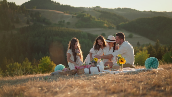 A happy family with children having picnic in park.