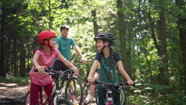 A young family with little children preapring for bike ride, standing with bicycles in nature.