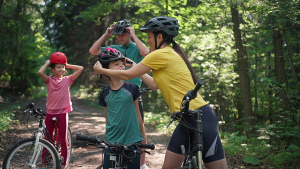 A young family with little children preapring for bike ride, standing with bicycles in nature.