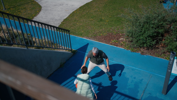 A happy father and teen daughter playing basketball outside at court.