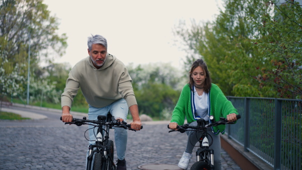 A happy father with teenage daughter on cycle ride in town.