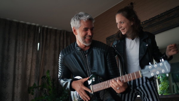 A father rock guitarist having fun and and dancing with his teenage daughter at home.