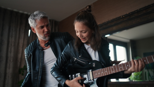 A father rock guitarist having fun and and dancing with his teenage daughter at home.