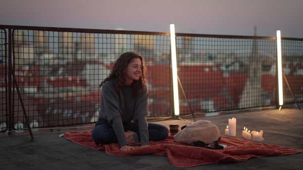 A happy young woman sitting on rooftop in the city.