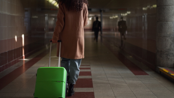 A woman traveler tourist going trough station with luggage holding cup of coffee.