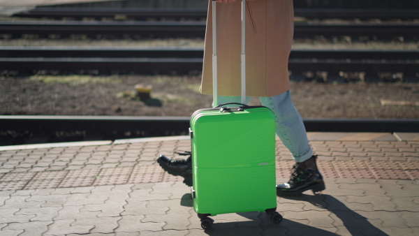 A woman traveler tourist waiting with luggage at train station, cut out.