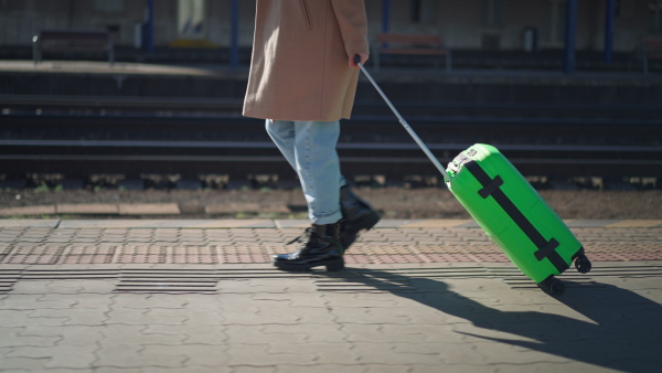 A woman traveler tourist waiting with luggage at train station, cut out.