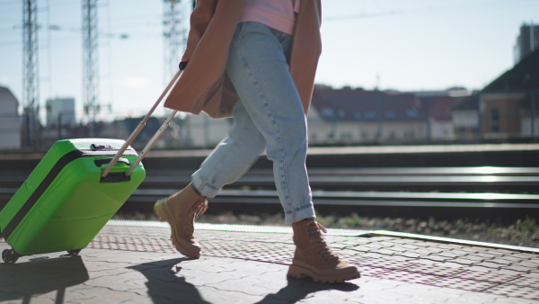 A woman traveler tourist waiting with luggage at train station, cut out.