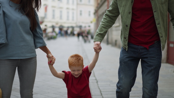 Youg parents with their little redhead son walking in a city.