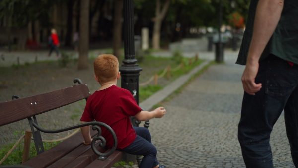 Father consoling his little upset son, outdoor in city park.