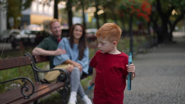 Little redhead boy doing bubbles with bubble blower, outdoor in a city park.