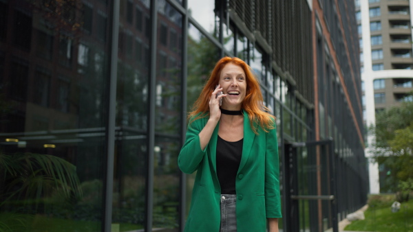 Young businesswoman walking in the city and calling.