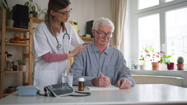 A healthcare worker or caregiver visiting senior man indoors at home.