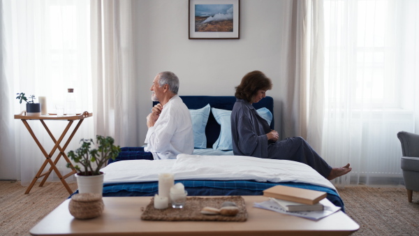 Senior couple sitting at a bed and prepairing for sleeping.