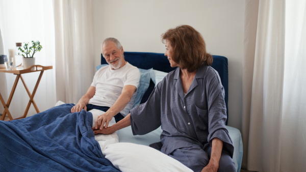 Senior couple sitting in bed and holding each other hand.