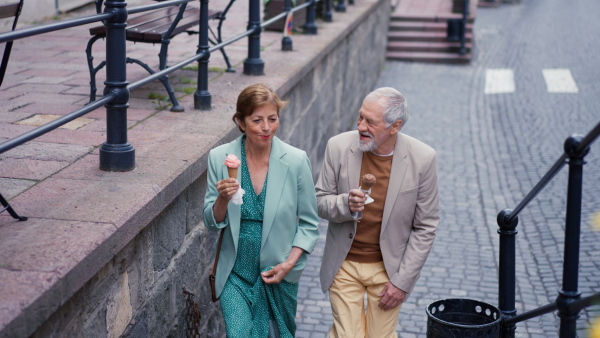 Attractive senior couple walking in street, eating ice cream.