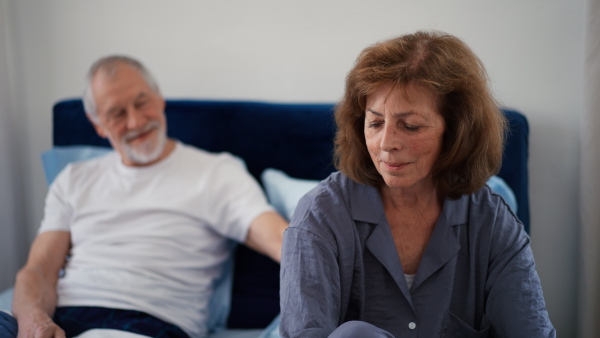 Senior man consoling his unhappy woman in bed.