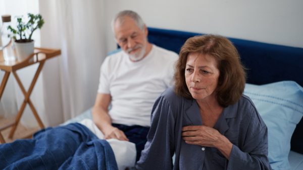 Senior man consoling his unhappy woman in bed.